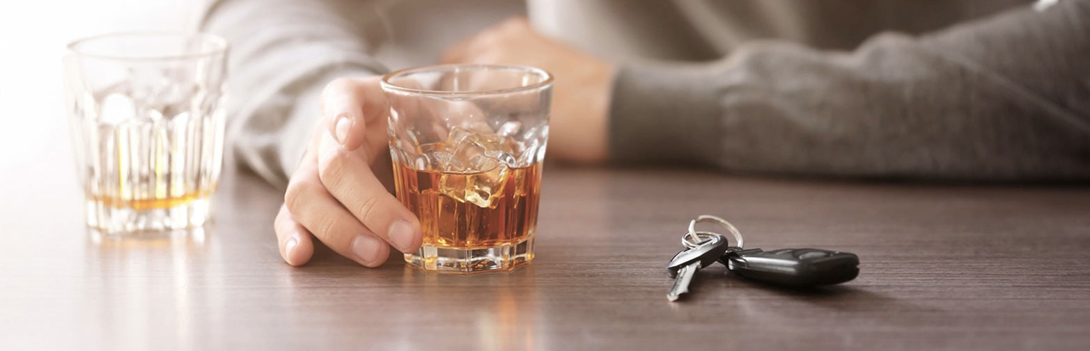 man holding whiskey glass with car keys