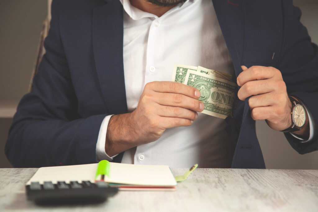 man putting money in pocket embezzlement